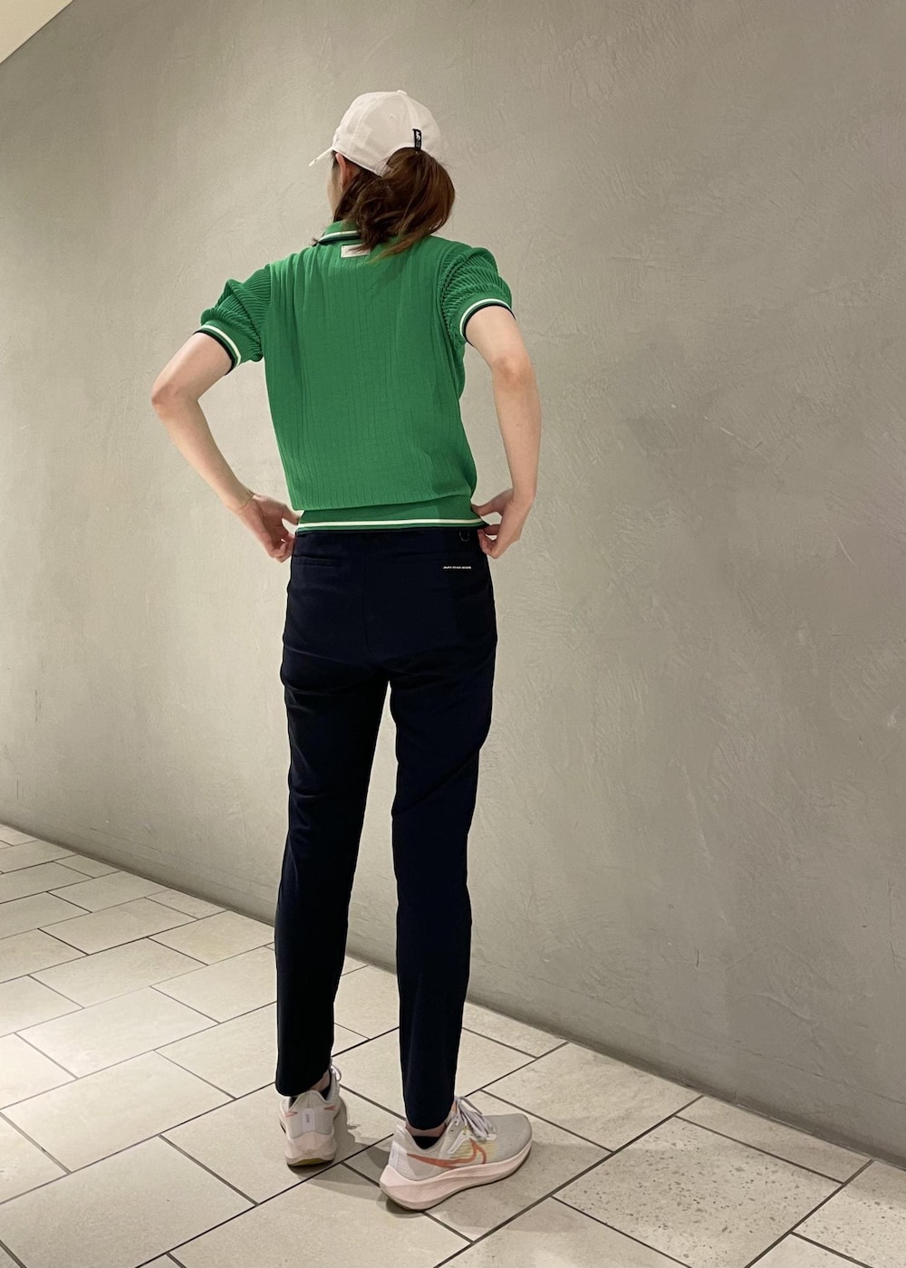 グリーン系のポロシャツ、ブルー系のその他パンツ、ホワイト系のキャップを着用したレディースの夏コーディネートの2枚目の写真