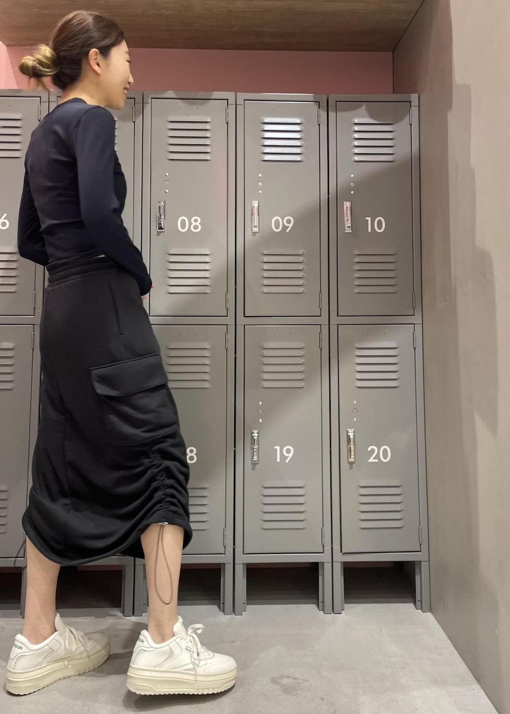 ブラック系のスカート、ブラック系のTシャツ/カットソー、ホワイト系のスニーカーを着用したレディースの冬コーディネートの3枚目の写真