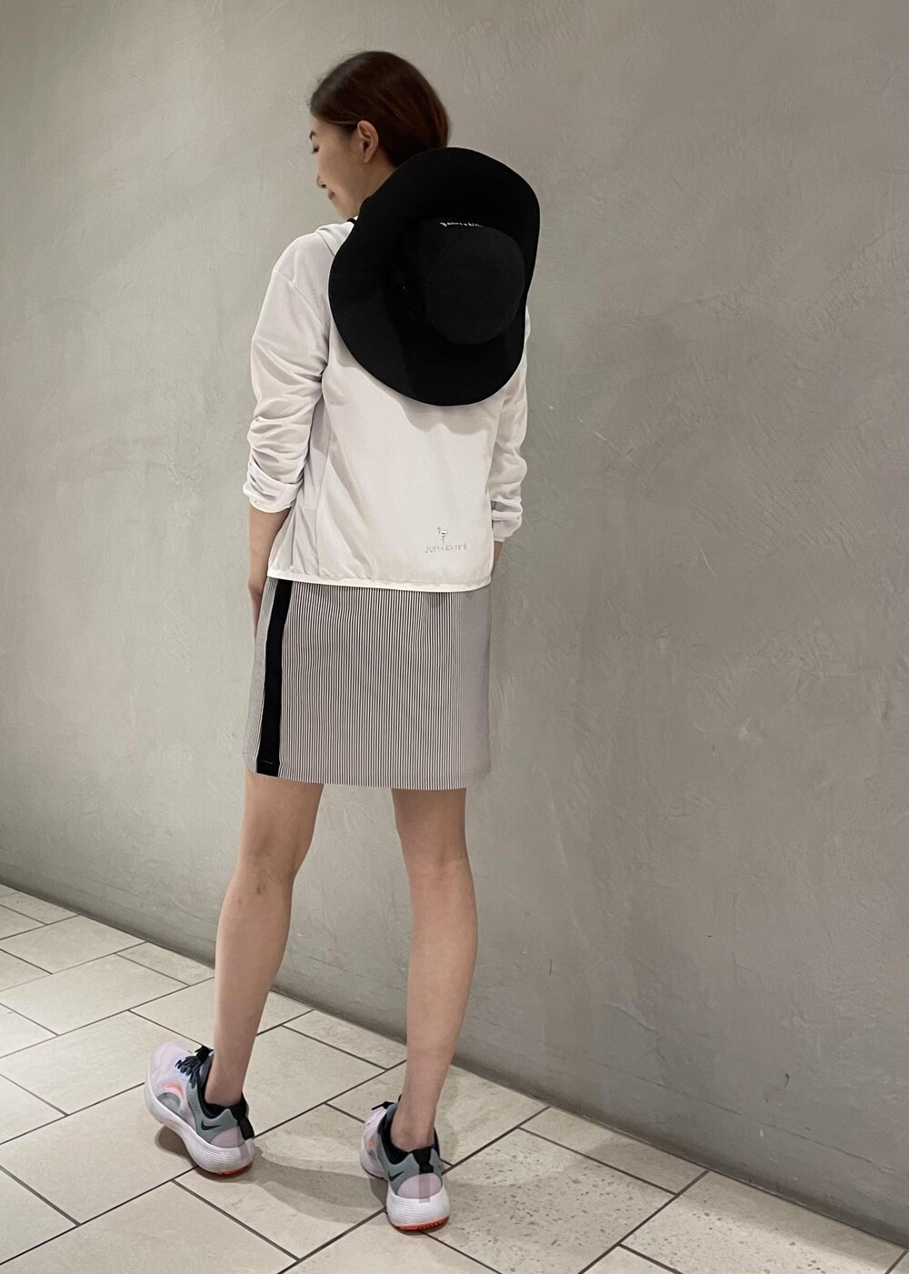 ブラック系のワンピース、ホワイト系のパーカー、ブラック系のハットを着用したレディースの春コーディネートの4枚目の写真