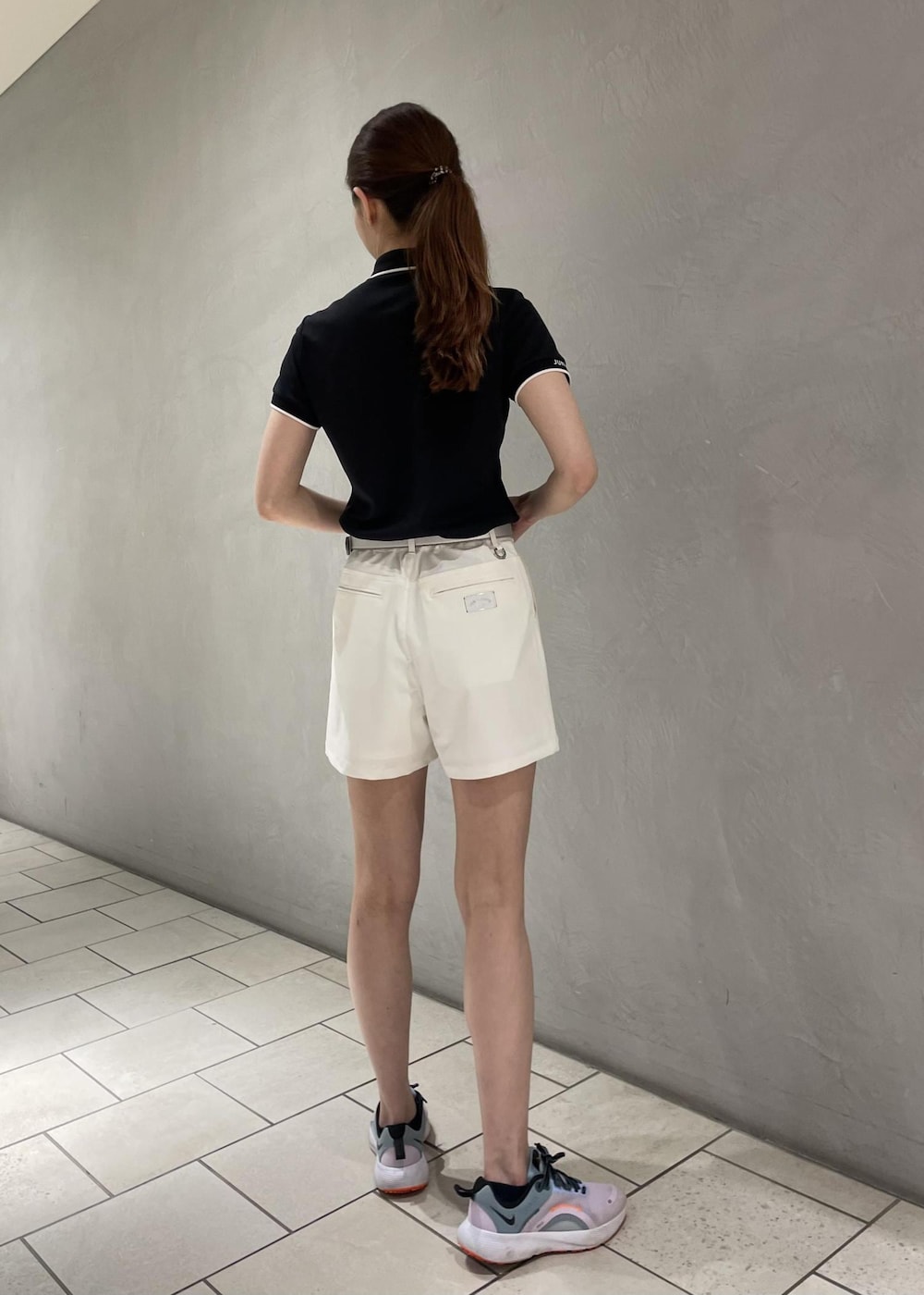 ブラック系のポロシャツ、ホワイト系のその他パンツ、シルバー系のベルトを着用したレディースの春コーディネートの2枚目の写真