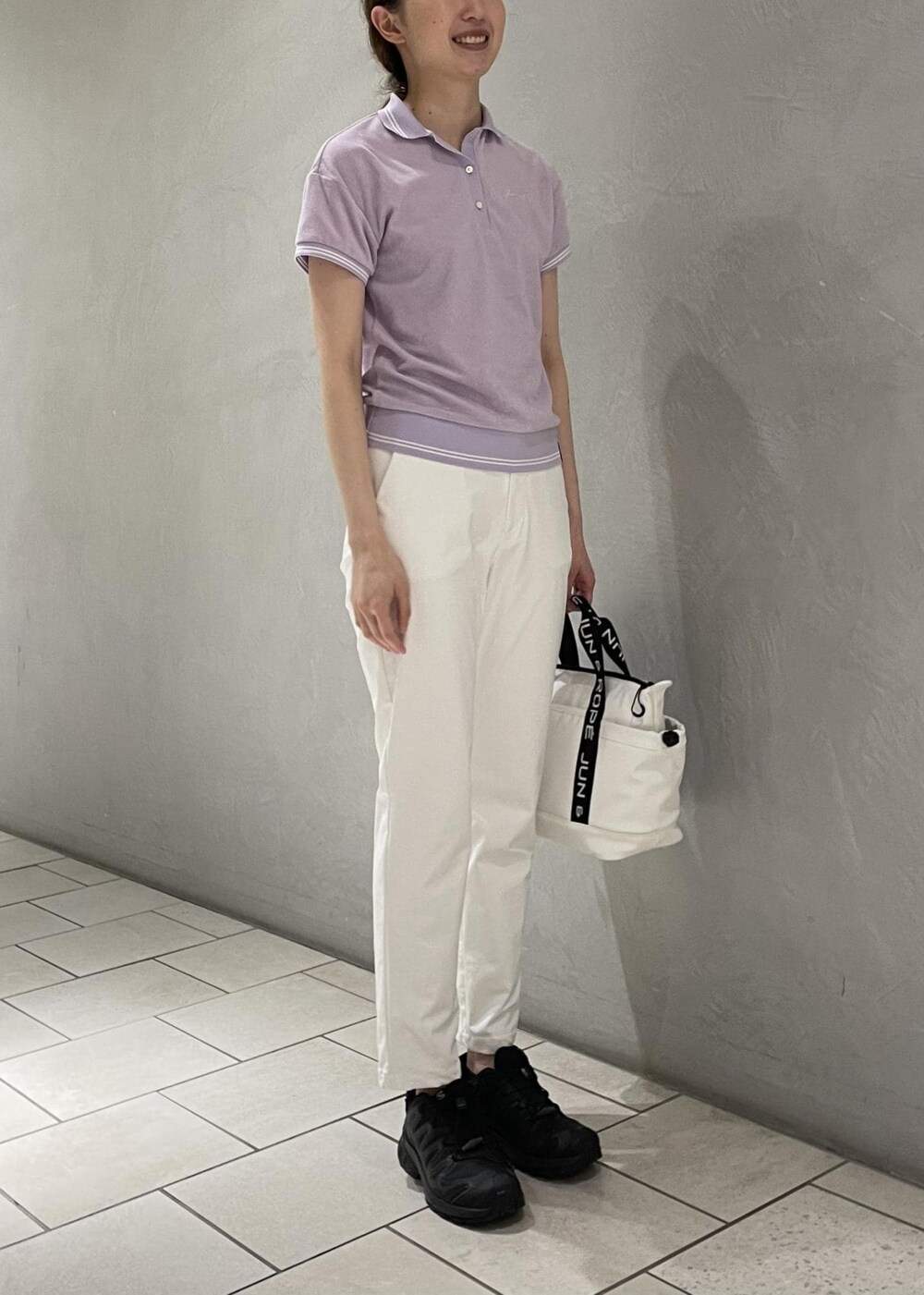 ホワイト系のハンドバッグ、ホワイト系のその他パンツ、パープル系のポロシャツを着用したレディースの春コーディネートの2枚目の写真