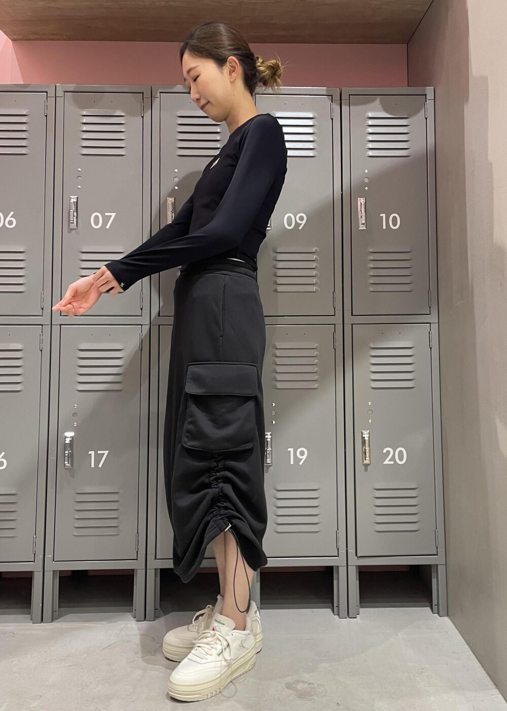 ブラック系のスカート、ブラック系のTシャツ/カットソー、ホワイト系のスニーカーを着用したレディースの冬コーディネートの2枚目の写真