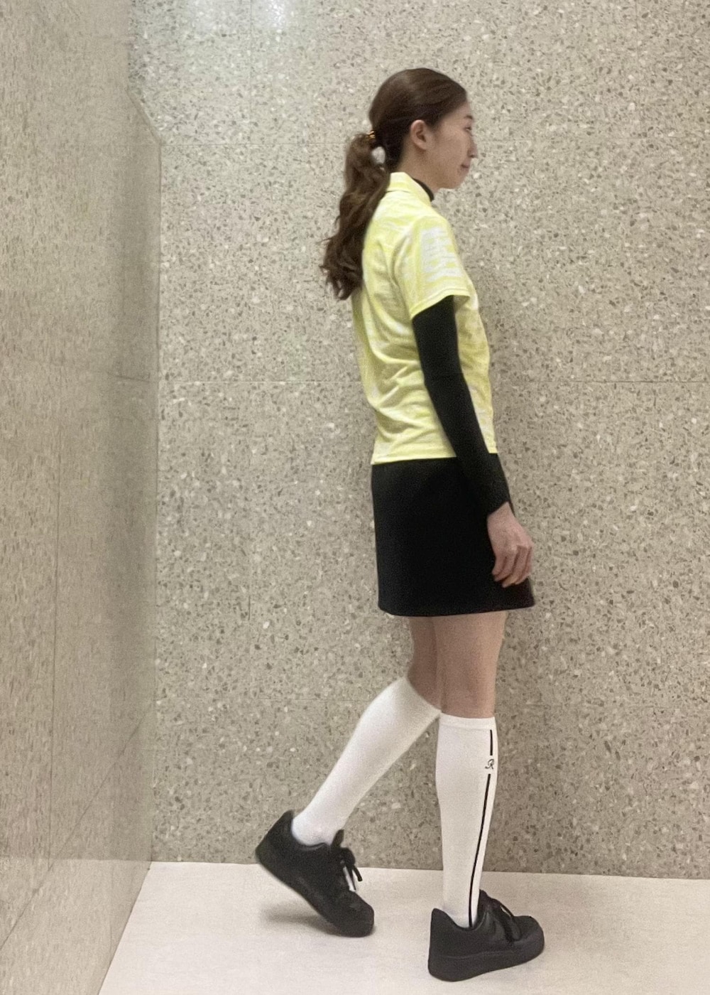 ブラック系のスカート、ブラック系のTシャツ/カットソー、イエロー系のポロシャツを着用したレディースの秋コーディネートの4枚目の写真
