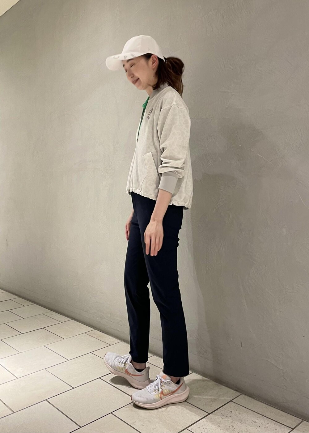 グレー系のブルゾン、グリーン系のポロシャツ、ブルー系のその他パンツを着用したレディースの夏コーディネートの2枚目の写真