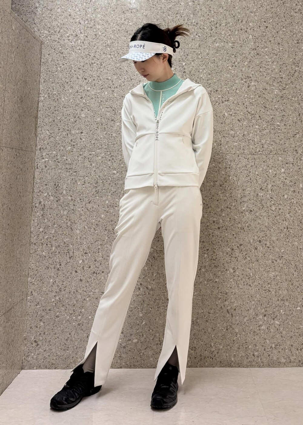 ホワイト系のブルゾン、グリーン系のニット/セーター、ホワイト系のサンバイザーを着用したレディースの冬コーディネートの2枚目の写真