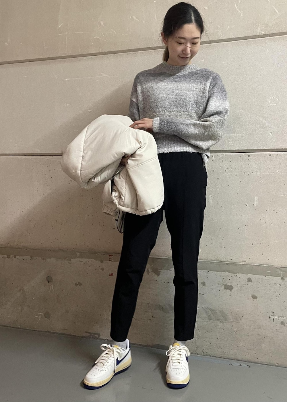 ブラック系のその他パンツ、ホワイト系のスニーカー、グレー系のニット/セーターを着用したレディースの冬コーディネートの2枚目の写真