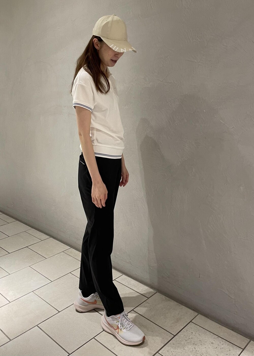 ホワイト系のポロシャツ、ブラック系のその他パンツ、ベージュ系のキャップを着用したレディースの春コーディネートの2枚目の写真