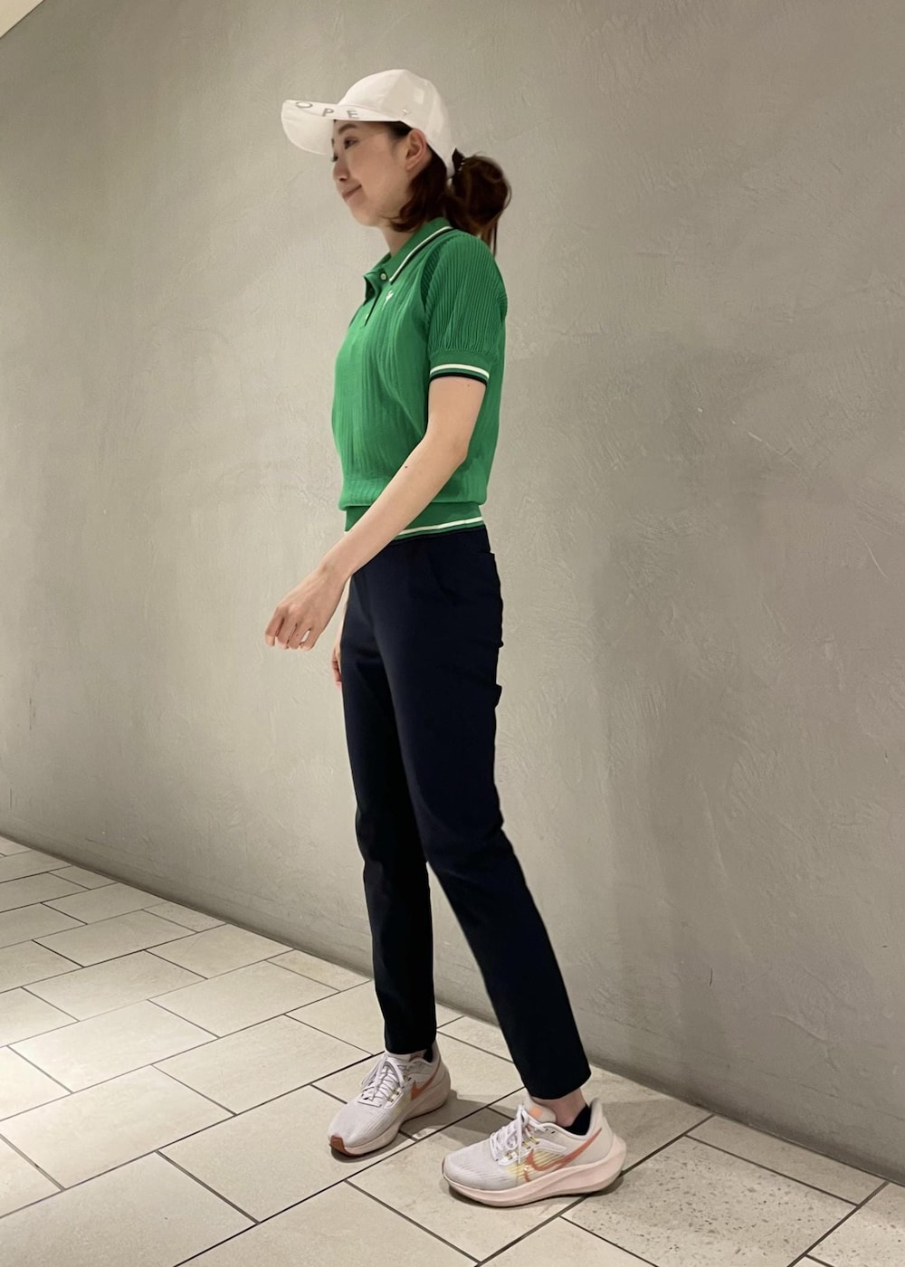 グリーン系のポロシャツ、ブルー系のその他パンツ、ホワイト系のキャップを着用したレディースの夏コーディネートの4枚目の写真