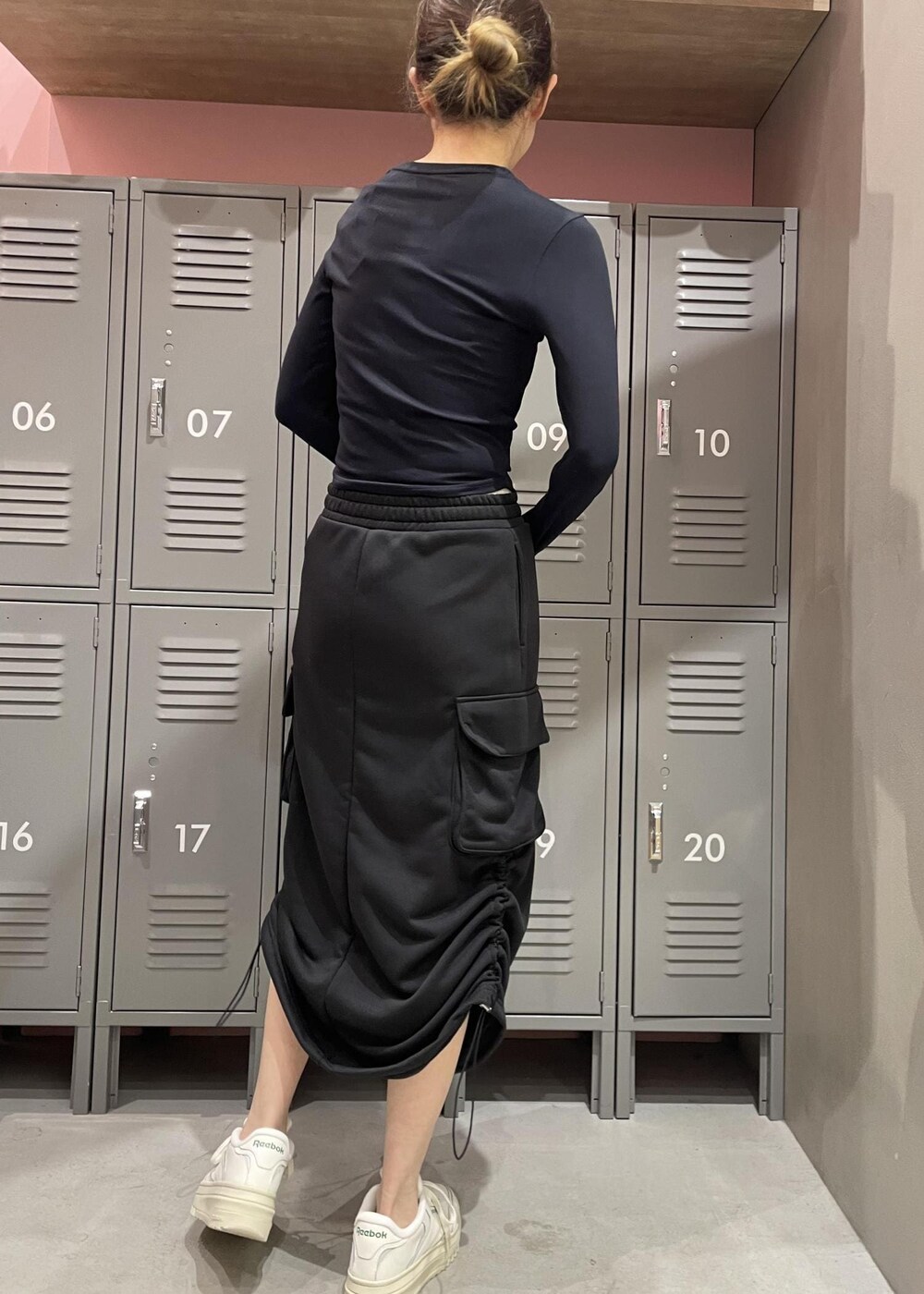 ブラック系のスカート、ブラック系のTシャツ/カットソー、ホワイト系のスニーカーを着用したレディースの冬コーディネートの4枚目の写真