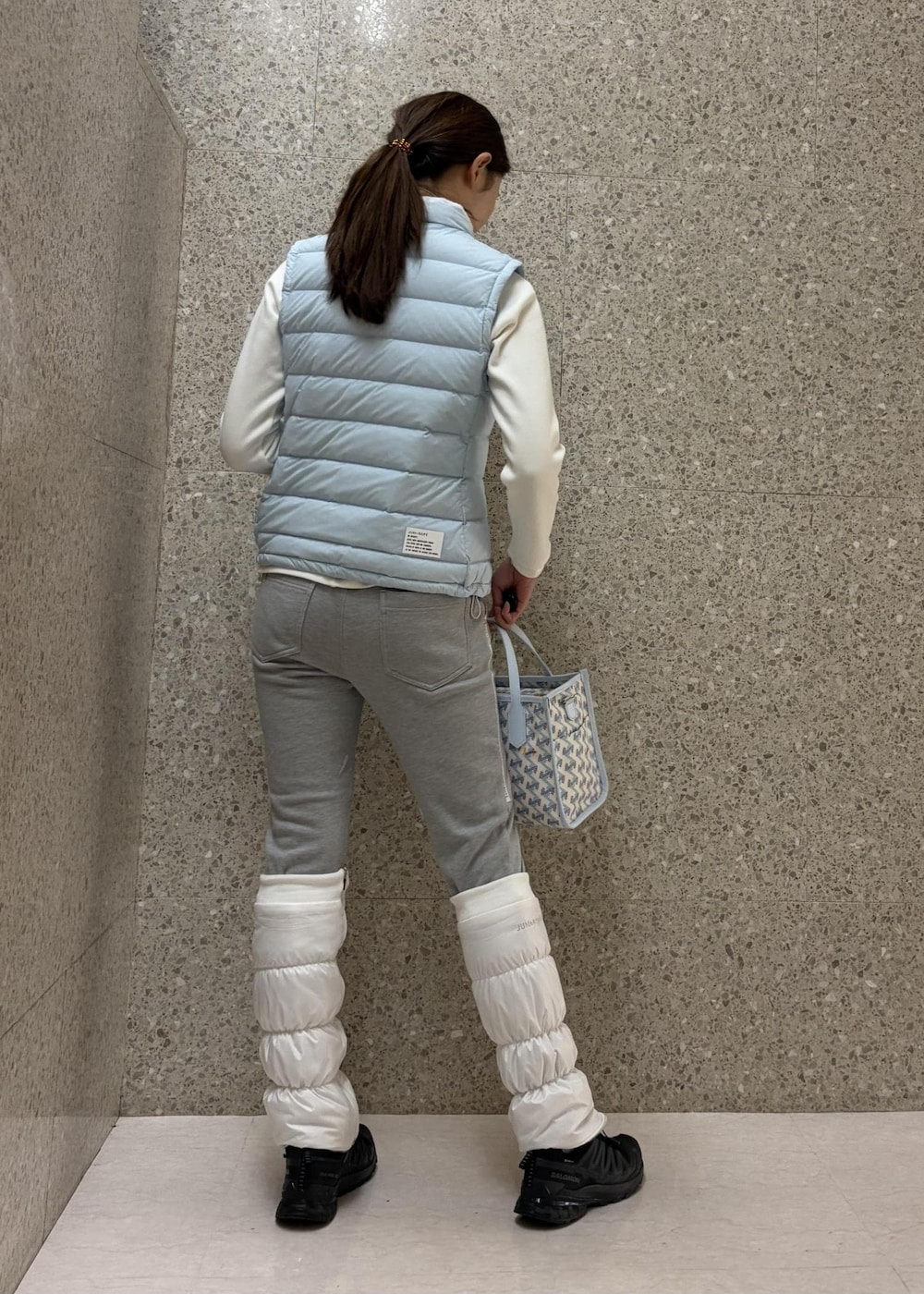 グレー系のその他パンツ、ブルー系のダウンベスト、ホワイト系のTシャツ/カットソーを着用したレディースの冬コーディネートの3枚目の写真