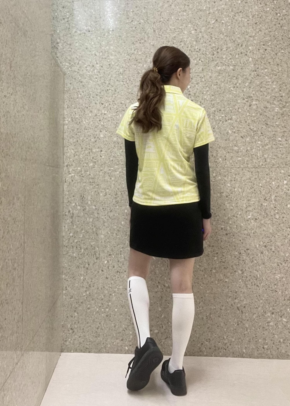 ブラック系のスカート、ブラック系のTシャツ/カットソー、イエロー系のポロシャツを着用したレディースの秋コーディネートの3枚目の写真