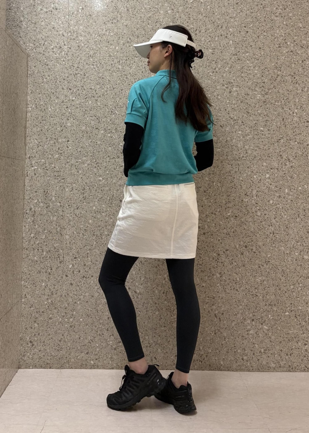 ホワイト系のスカート、ブルー系のポロシャツ、ホワイト系のサンバイザーを着用したレディースの春コーディネートの4枚目の写真
