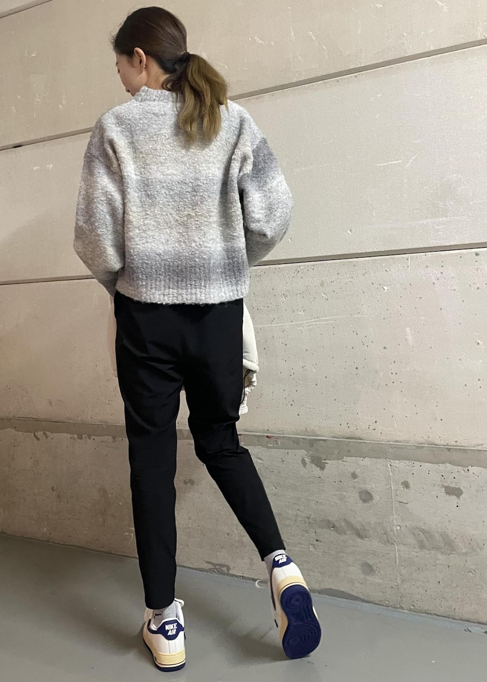 ブラック系のその他パンツ、ホワイト系のスニーカー、グレー系のニット/セーターを着用したレディースの冬コーディネートの3枚目の写真