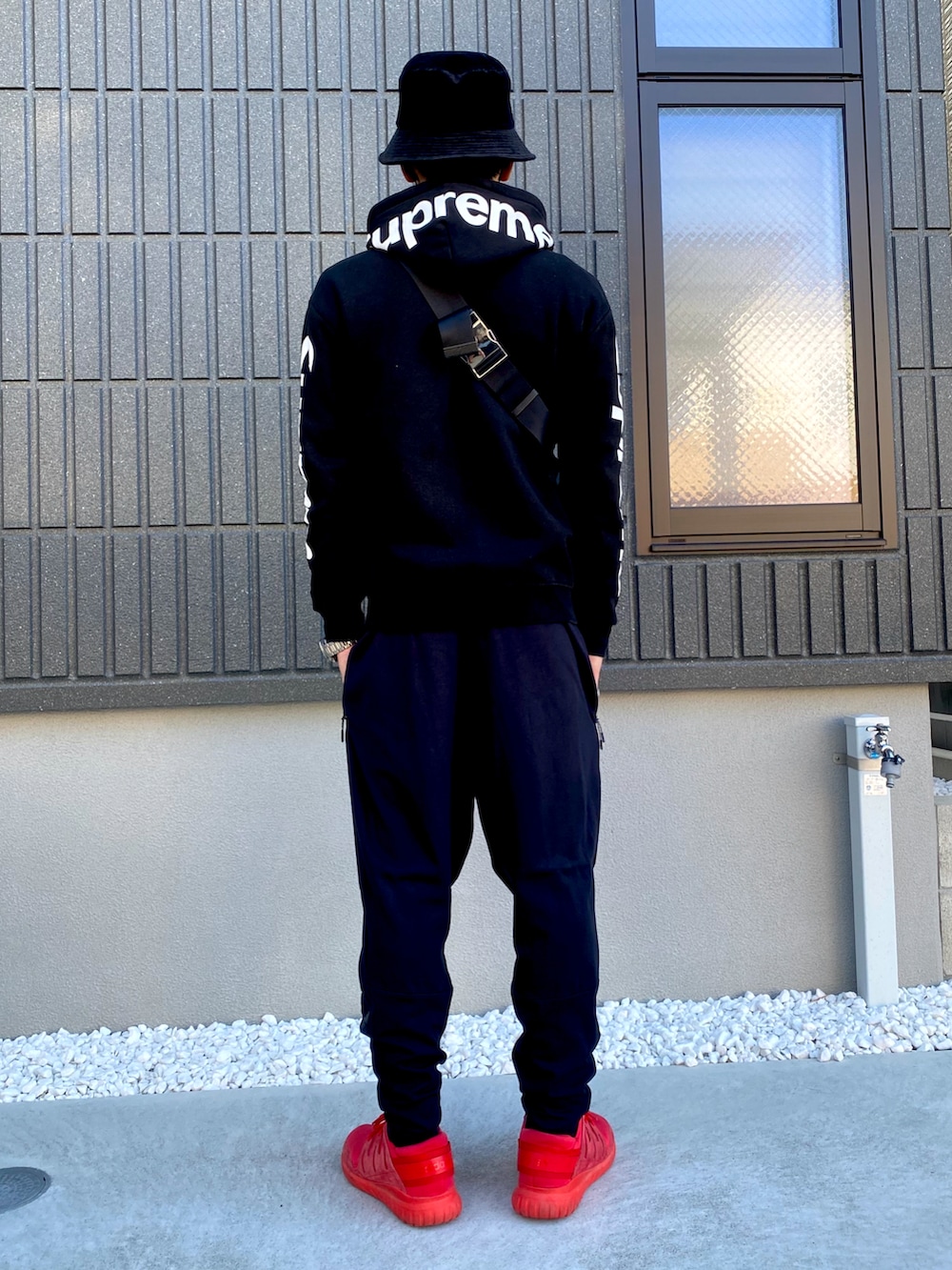 ブラック系のボディバッグ/ウエストポーチ、ブラック系のその他パンツ、レッド系のシューズを着用したメンズの冬コーディネートの2枚目の写真