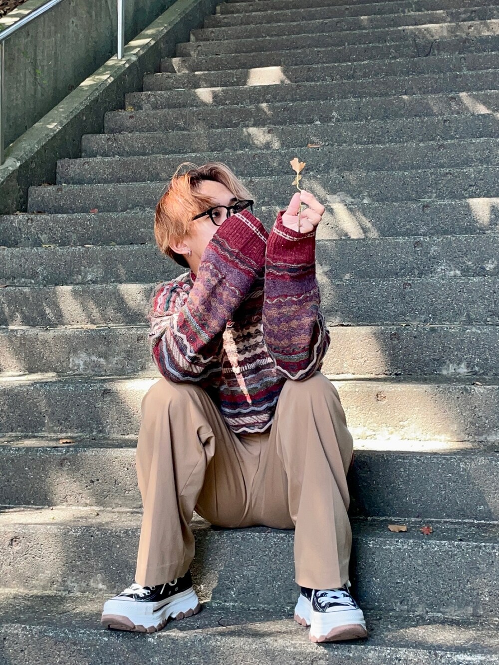 ブラック系のスニーカー、ベージュ系のスラックスを着用したメンズの秋コーディネートの3枚目の写真