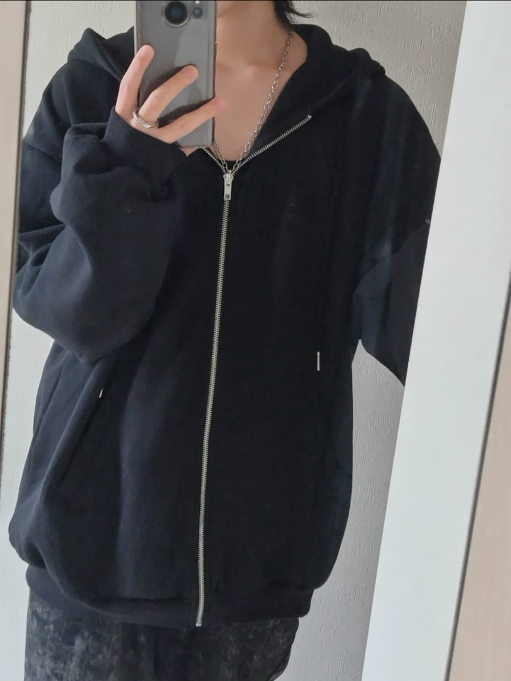 ブラック系のパーカー、ブラック系のデニムパンツ、シルバー系のネックレスを着用したメンズの春コーディネートの3枚目の写真