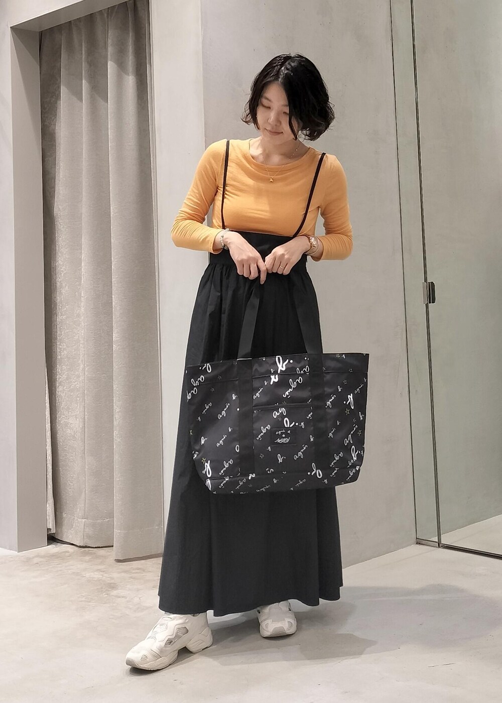 ベージュ系のスニーカー、ブラック系のトートバッグ、オレンジ系のアンサンブルを着用したレディースの秋コーディネートの4枚目の写真