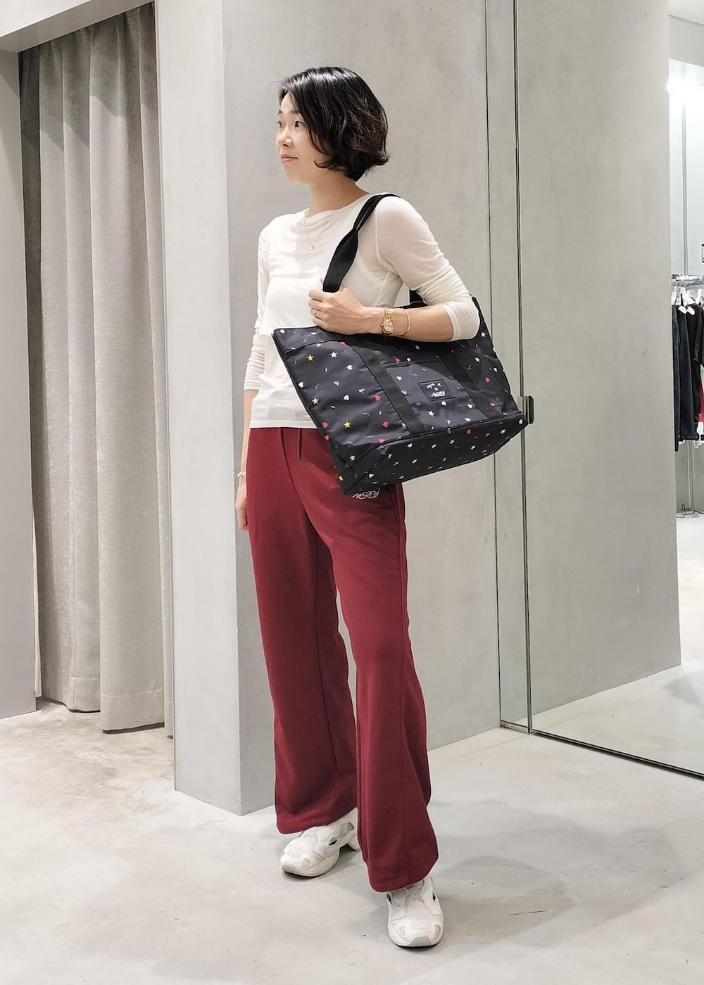 ベージュ系のスニーカー、ブラック系のトートバッグ、レッド系のその他パンツを着用したレディースの秋コーディネートの2枚目の写真