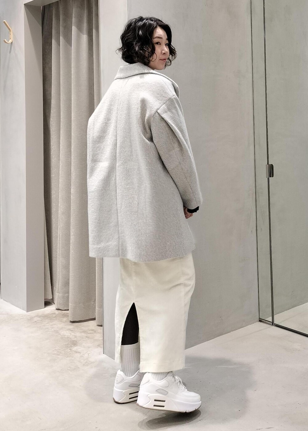 ホワイト系のスカート、ホワイト系のキャミソール、ブラック系のニット/セーターを着用したレディースの冬コーディネートの2枚目の写真