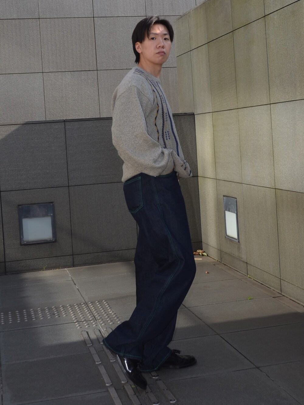 ブラック系のローファー、ブルー系のデニムパンツ、グレー系のニット/セーターを着用したメンズの冬コーディネートの2枚目の写真