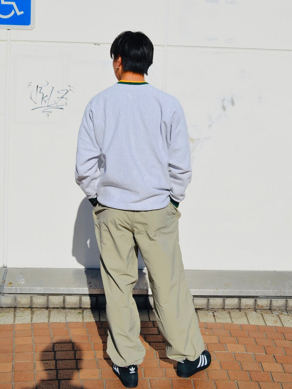 ブラック系のスニーカー、ベージュ系のパンツ、ホワイト系のトップスを着用したメンズの冬コーディネートの2枚目の写真