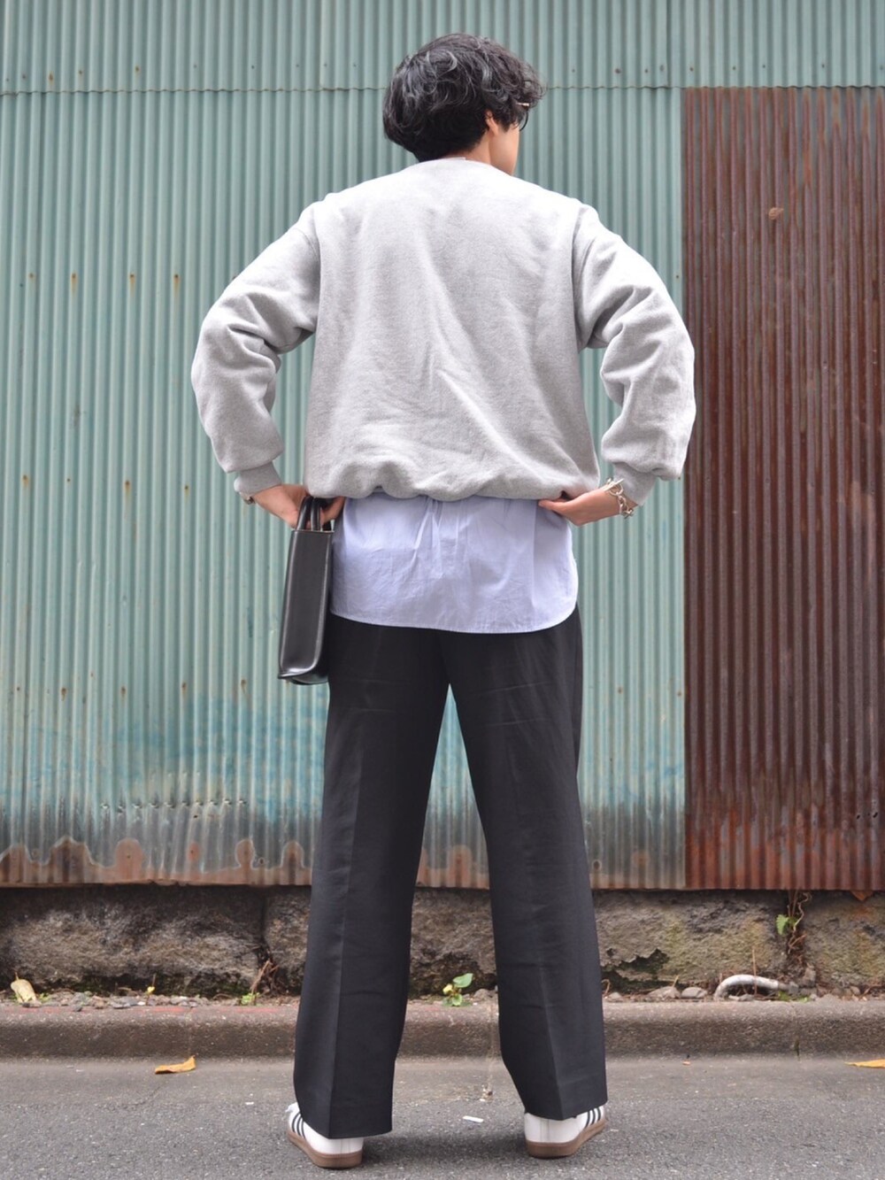 ブラック系のハンドバッグ、ホワイト系のスニーカー、ブラック系のスラックスを着用したメンズの冬コーディネートの2枚目の写真