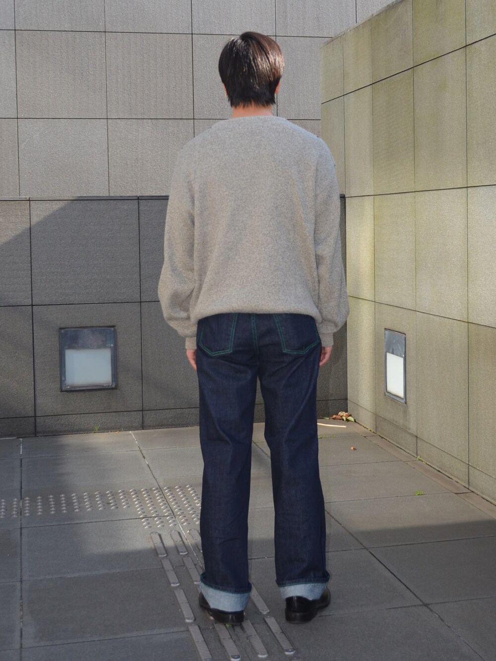 ブラック系のローファー、ブルー系のデニムパンツ、グレー系のニット/セーターを着用したメンズの冬コーディネートの3枚目の写真