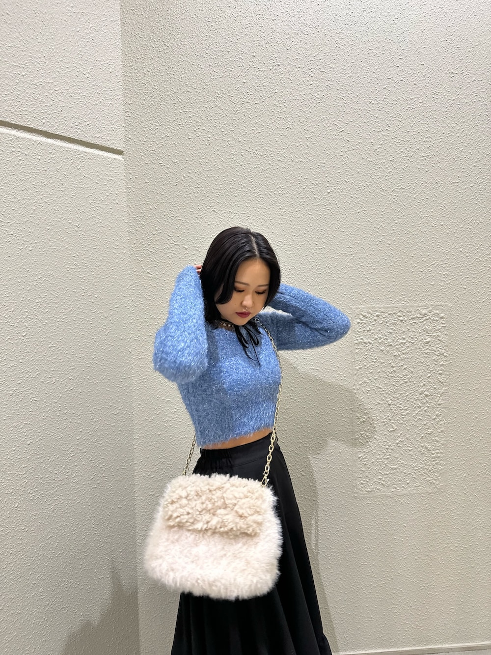 ブラック系のスカート、ホワイト系のハンドバッグ、ブルー系のニット/セーターを着用したレディースの冬コーディネートの3枚目の写真