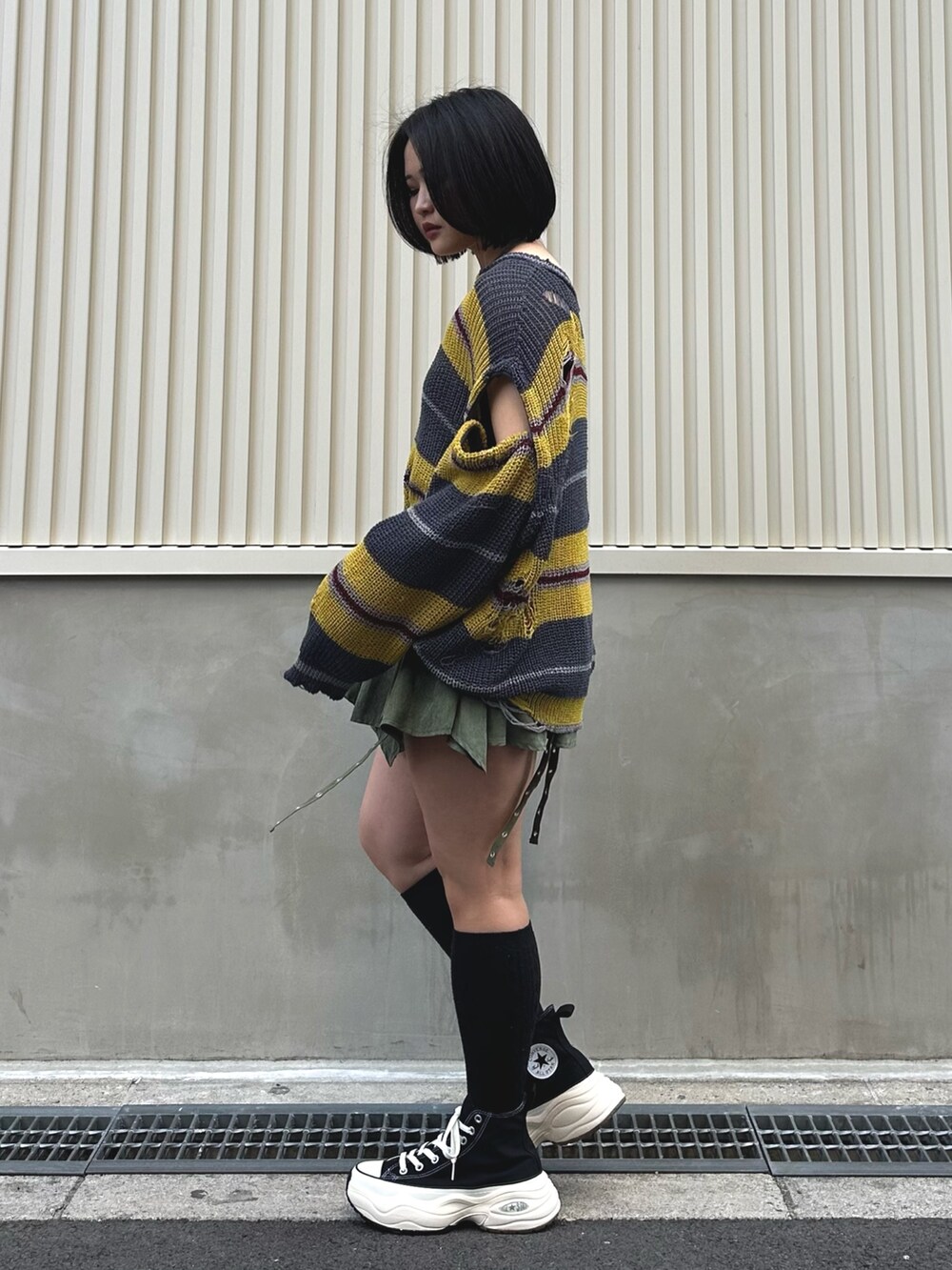 ブラック系のニット/セーター、グリーン系のスカート、シルバー系のネックレスを着用したレディースの春コーディネートの3枚目の写真