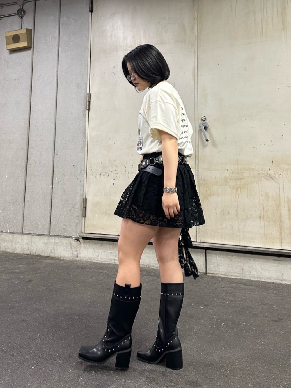ブラック系のブーツ、ホワイト系のTシャツ/カットソー、ブラック系のスカートを着用したレディースの夏コーディネートの2枚目の写真