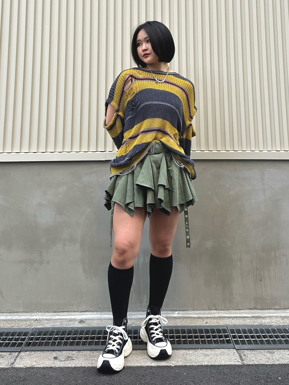 ブラック系のニット/セーター、グリーン系のスカート、シルバー系のネックレスを着用したレディースの春コーディネートの2枚目の写真