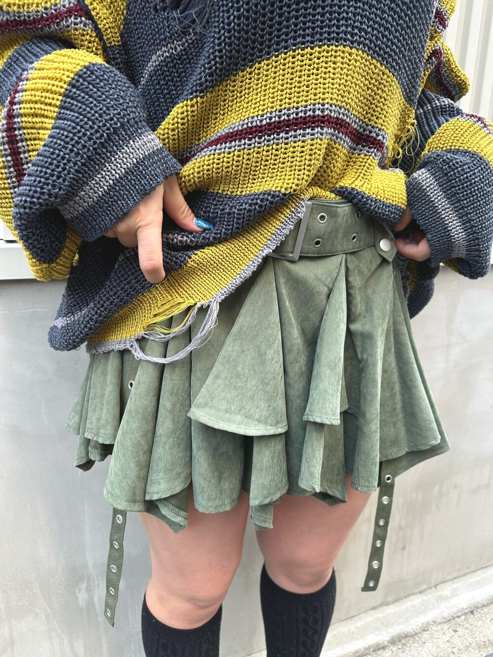 ブラック系のニット/セーター、グリーン系のスカート、シルバー系のネックレスを着用したレディースの春コーディネートの7枚目の写真