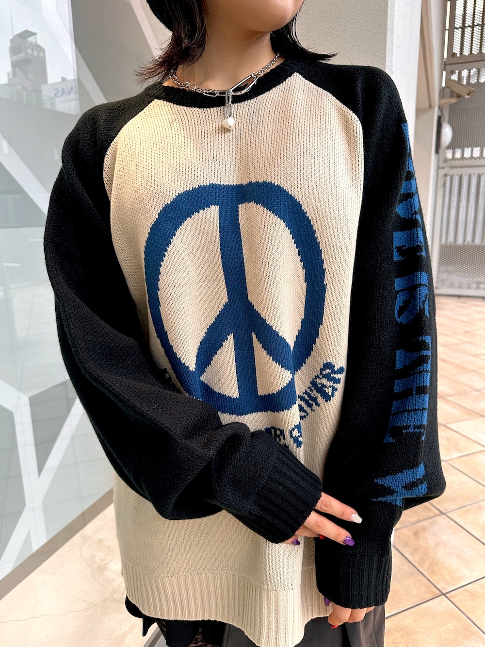 ホワイト系のニット/セーター、ブラック系のスカート、シルバー系のネックレスを着用したレディースの冬コーディネートの5枚目の写真