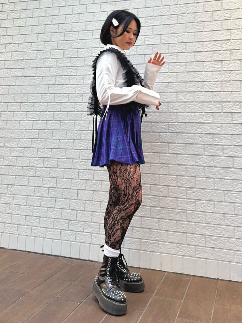 パープル系のスカート、ホワイト系のシャツ/ブラウス、ブラック系のサスペンダーを着用したレディースの冬コーディネートの2枚目の写真