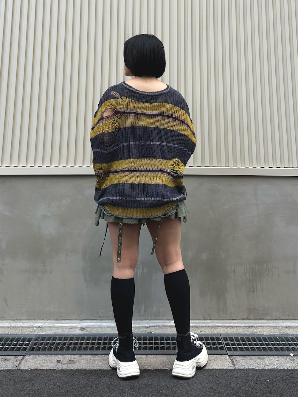 ブラック系のニット/セーター、グリーン系のスカート、シルバー系のネックレスを着用したレディースの春コーディネートの4枚目の写真