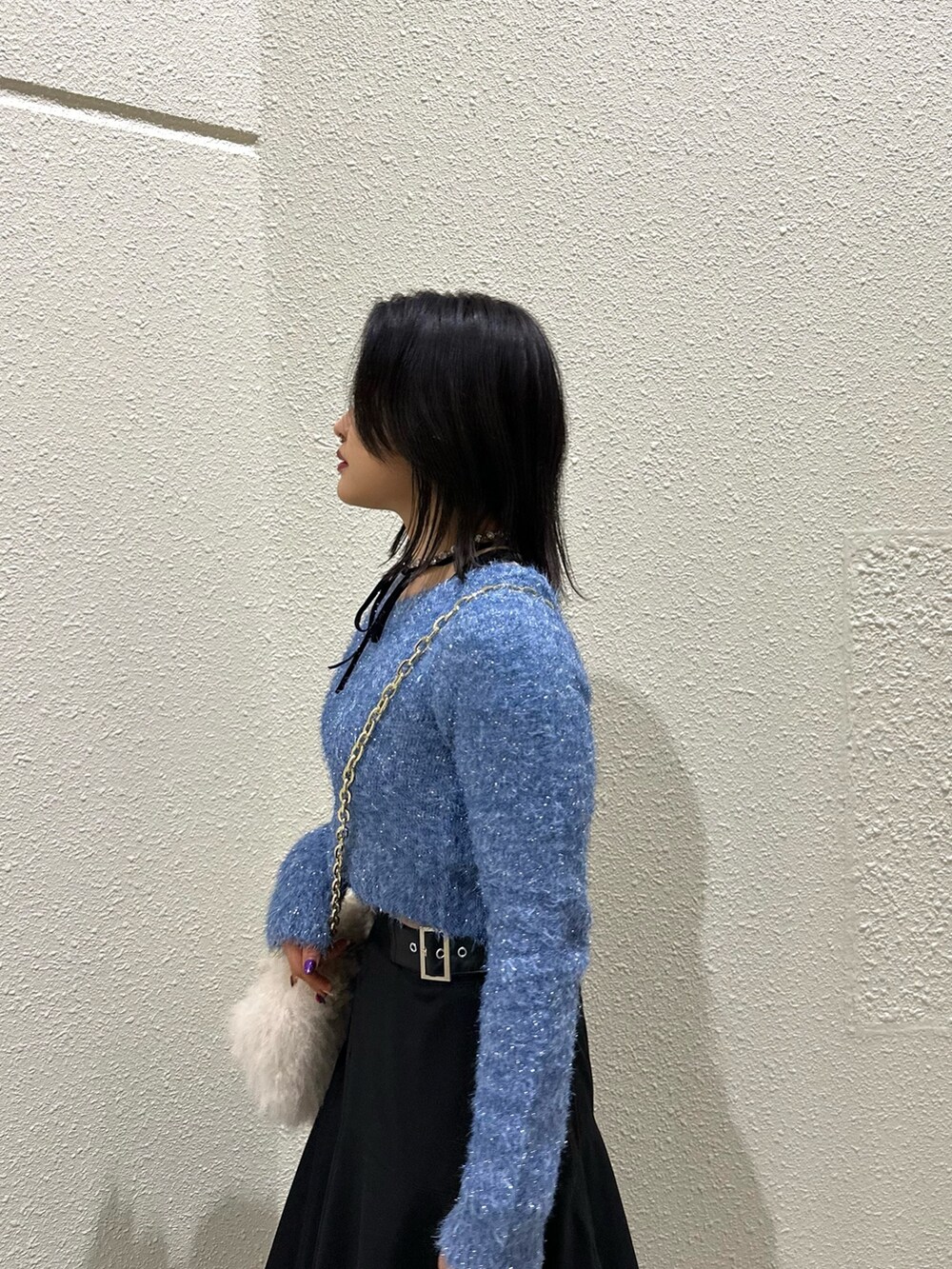 ブラック系のスカート、ホワイト系のハンドバッグ、ブルー系のニット/セーターを着用したレディースの冬コーディネートの4枚目の写真