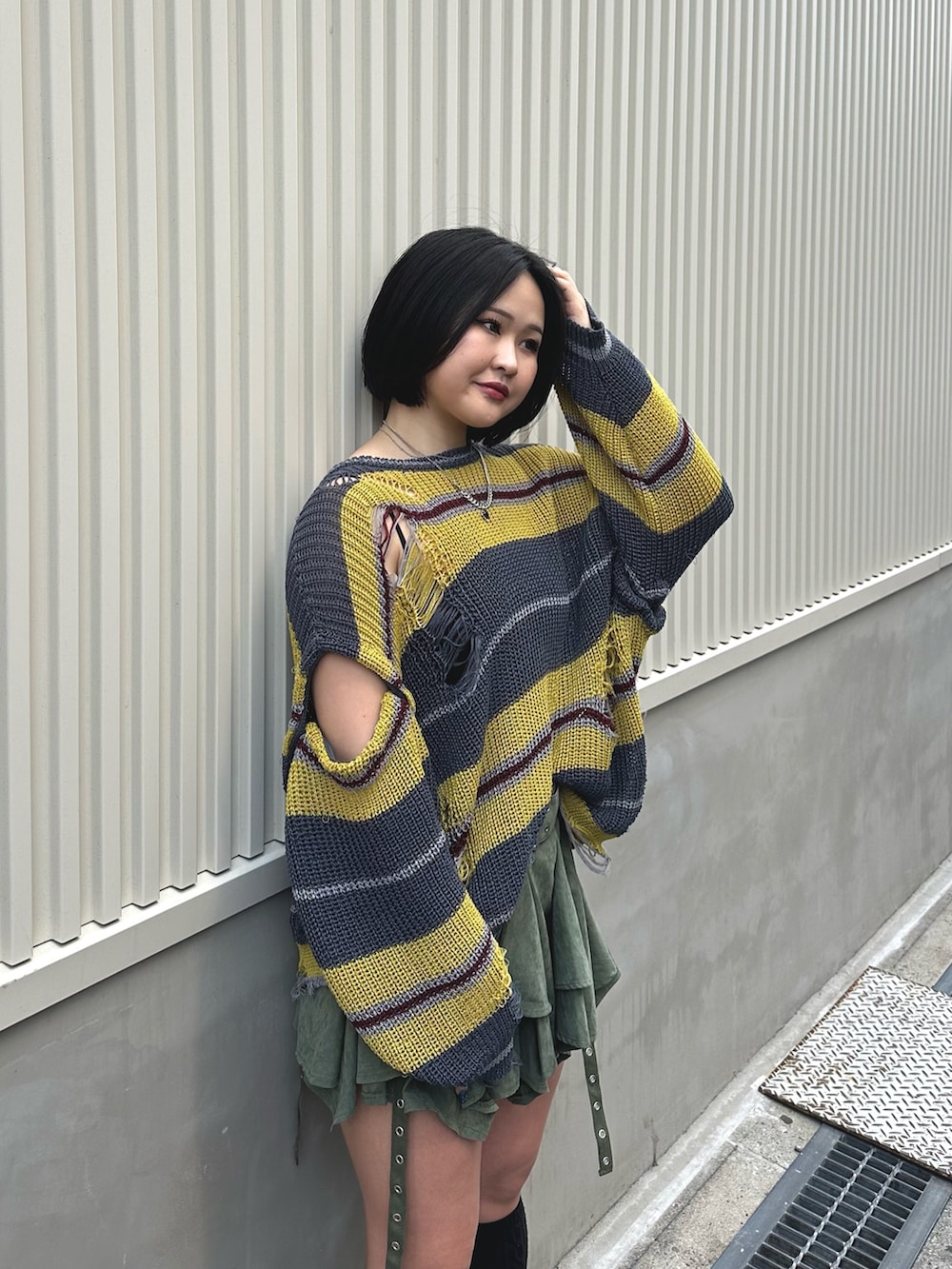 ブラック系のニット/セーター、グリーン系のスカート、シルバー系のネックレスを着用したレディースの春コーディネートの5枚目の写真