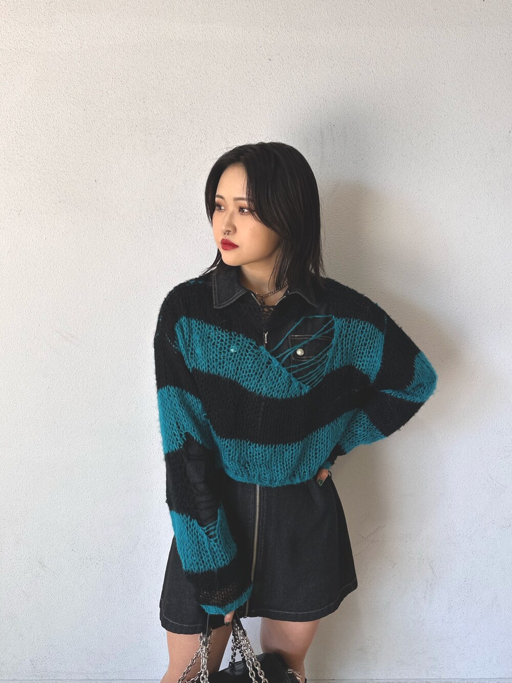 ブラック系のニット/セーター、ブラック系のワンピース、ブラック系のハンドバッグを着用したレディースの秋コーディネートの3枚目の写真