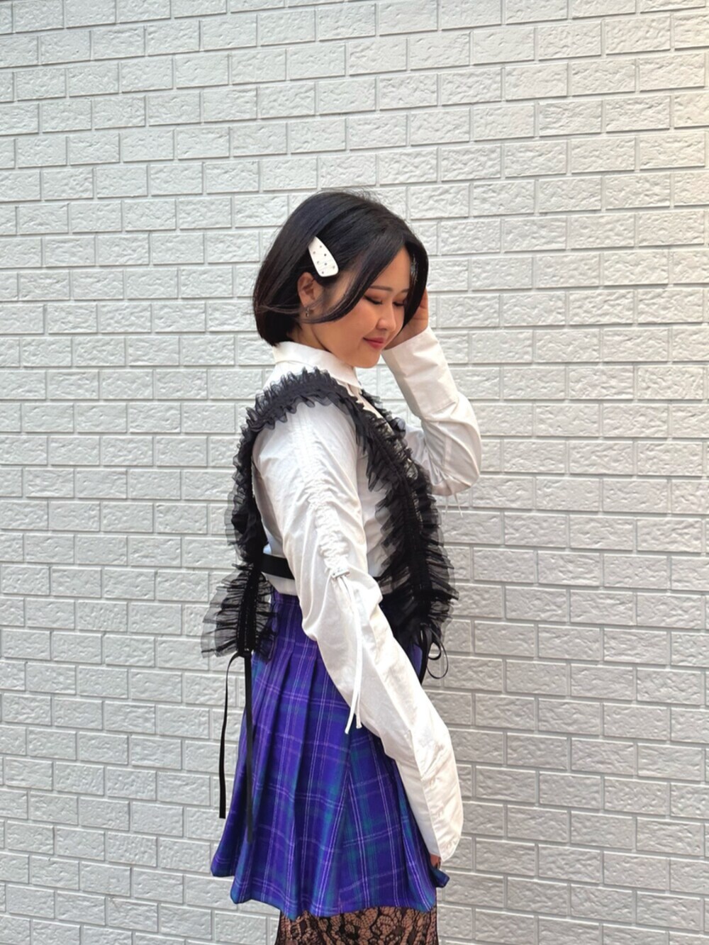 パープル系のスカート、ホワイト系のシャツ/ブラウス、ブラック系のサスペンダーを着用したレディースの冬コーディネートの4枚目の写真