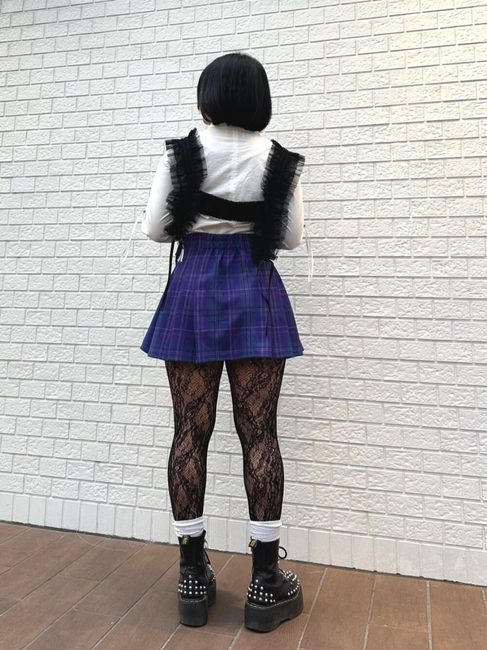 パープル系のスカート、ホワイト系のシャツ/ブラウス、ブラック系のサスペンダーを着用したレディースの冬コーディネートの3枚目の写真