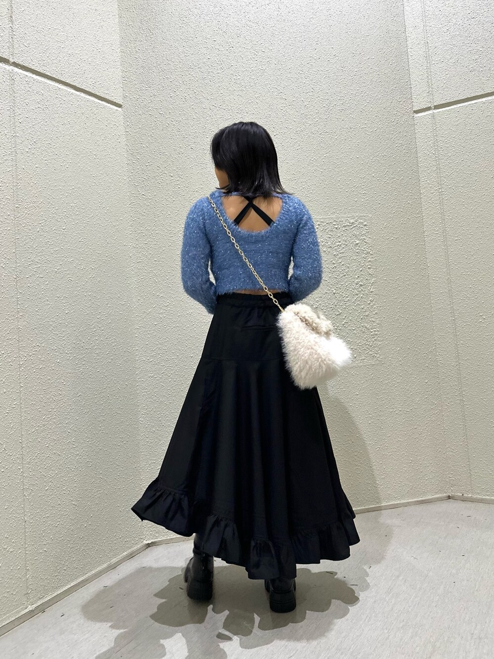 ブラック系のスカート、ホワイト系のハンドバッグ、ブルー系のニット/セーターを着用したレディースの冬コーディネートの2枚目の写真