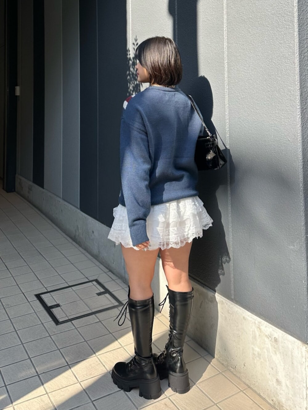 ブラック系のブーツ、ブルー系のニット/セーター、ホワイト系のその他パンツを着用したレディースの冬コーディネートの4枚目の写真