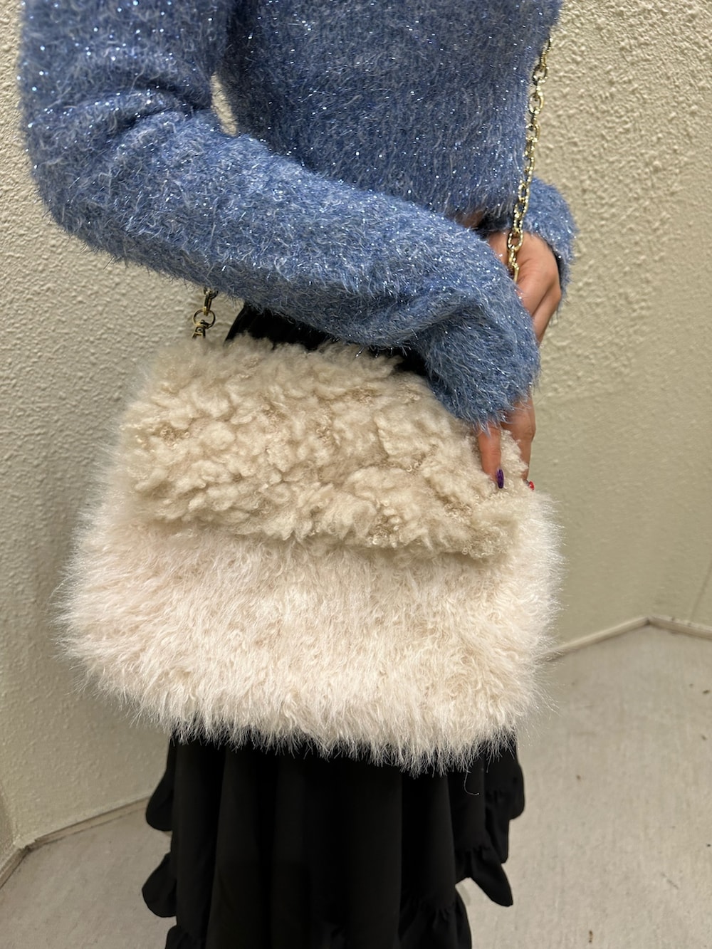 ブラック系のスカート、ホワイト系のハンドバッグ、ブルー系のニット/セーターを着用したレディースの冬コーディネートの6枚目の写真