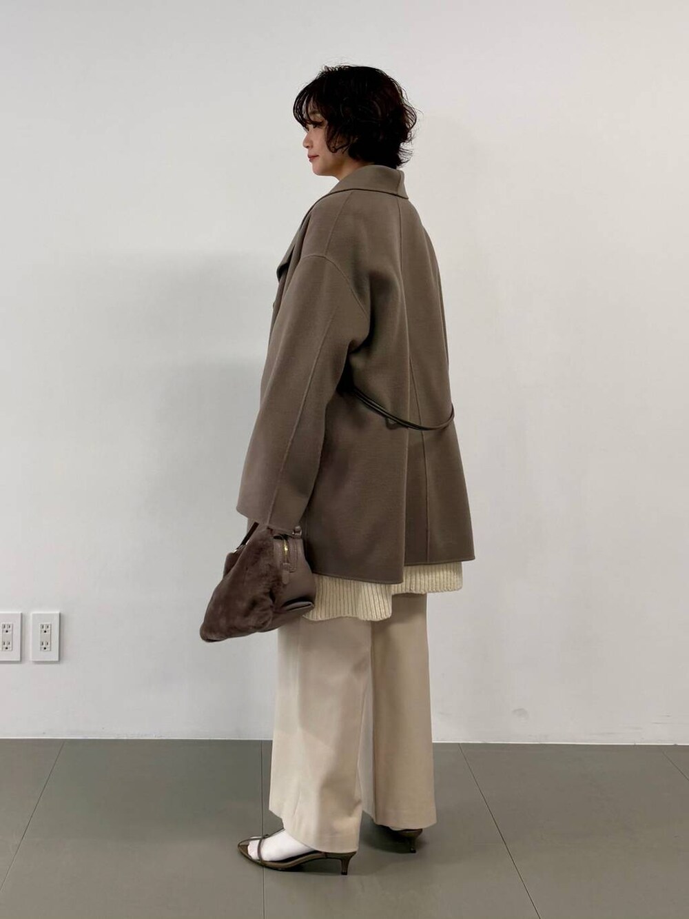 ベージュ系のその他パンツ、ベージュ系のハンドバッグ、ブラウン系のピーコートを着用したレディースの秋コーディネートの2枚目の写真