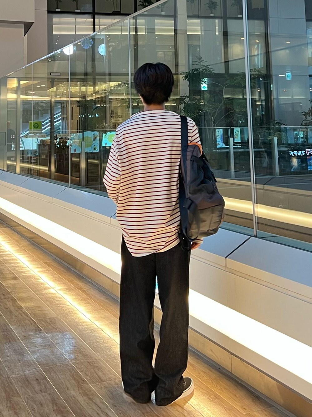 レッド系のTシャツ/カットソー、ブラウン系のトートバッグ、ブラック系のスニーカーを着用したメンズの秋コーディネートの3枚目の写真