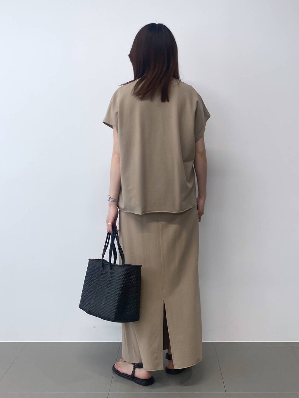 ブラック系のトートバッグ、ブラウン系のサンダル、ベージュ系のTシャツ/カットソーを着用したレディースの春コーディネートの3枚目の写真