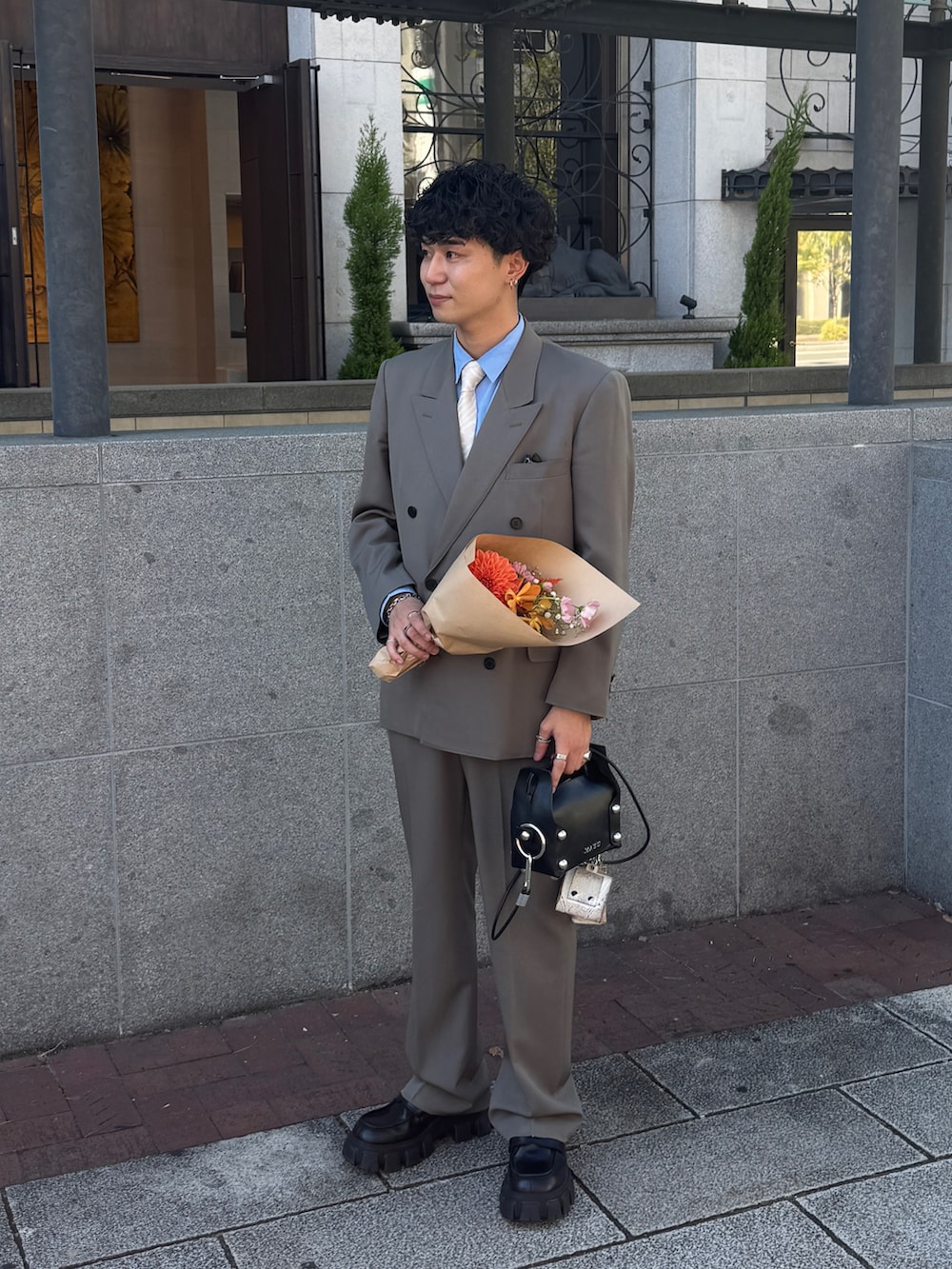 グレー系のテーラードジャケット、グレー系のスラックス、ブラック系のショルダーバッグを着用したメンズの秋コーディネートの2枚目の写真