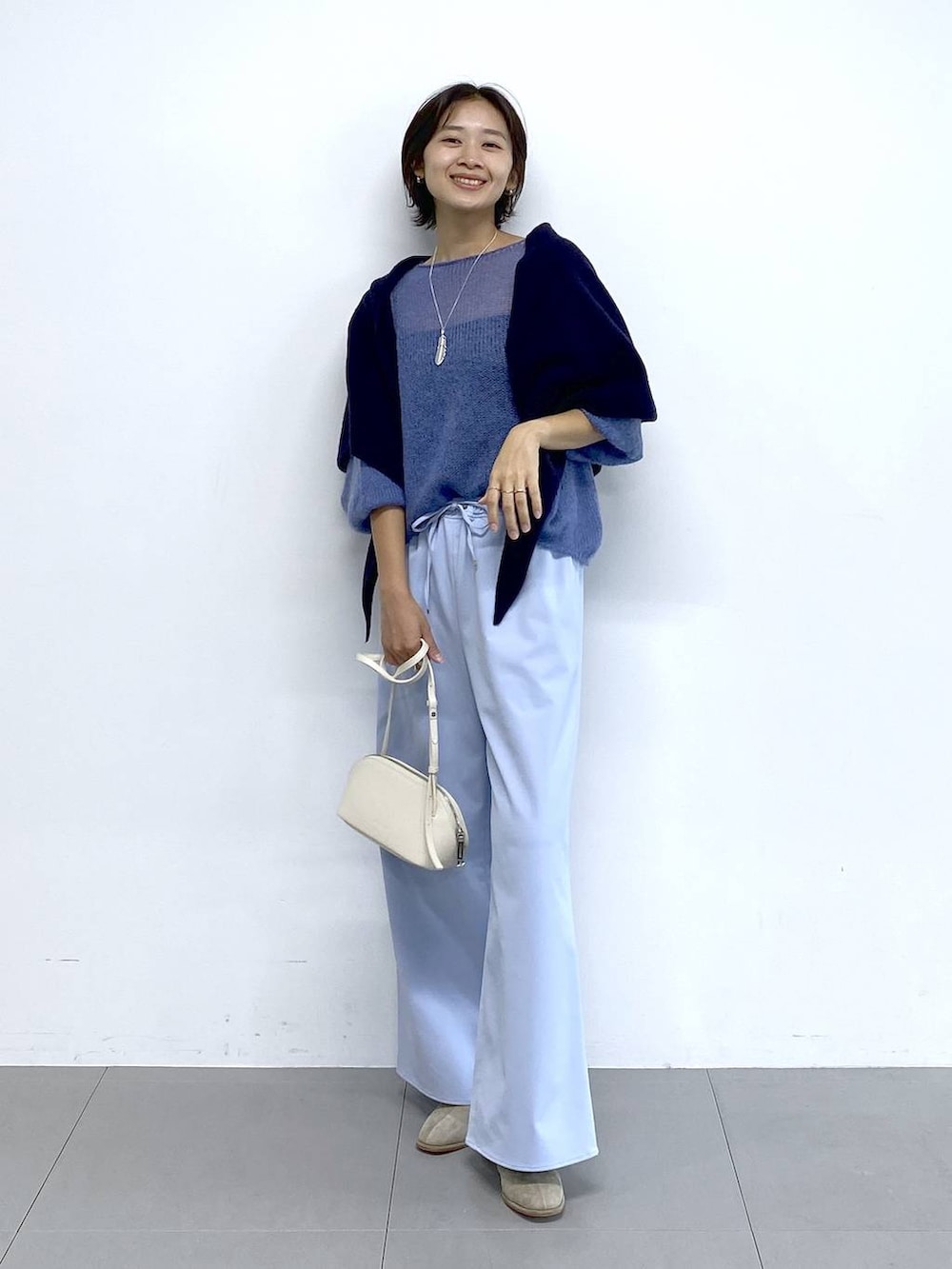 ホワイト系のショルダーバッグ、ベージュ系のブーツ、ブルー系のその他パンツを着用したレディースの秋コーディネートの2枚目の写真