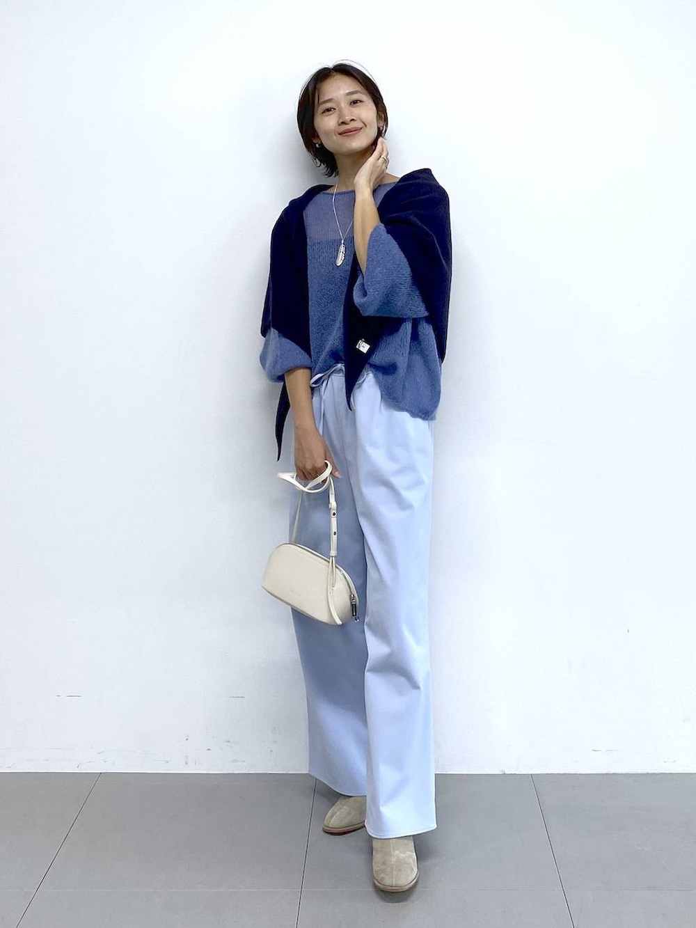 ホワイト系のショルダーバッグ、ベージュ系のブーツ、ブルー系のその他パンツを着用したレディースの秋コーディネートの5枚目の写真