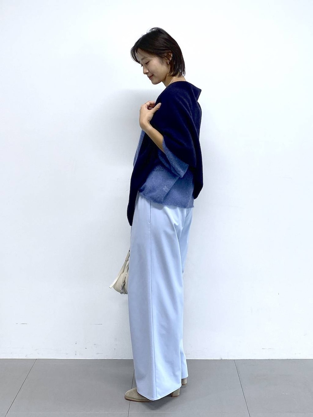 ホワイト系のショルダーバッグ、ベージュ系のブーツ、ブルー系のその他パンツを着用したレディースの秋コーディネートの3枚目の写真